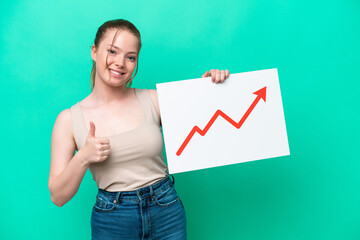 Young caucasian woman isolated on green background holding a sign with a growing statistics arrow...