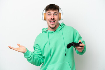 Young handsome man playing with a video game controller isolated on white background with shocked facial expression