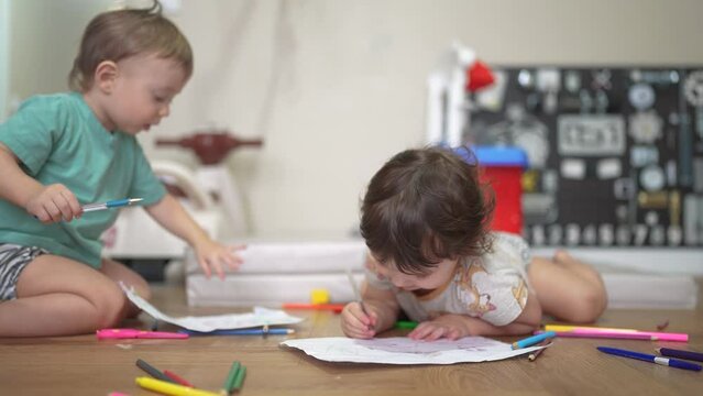 children sit on the floor and draw on paper. happy family child dream concept. baby boy and girl sitting indoors on the floor and drawing with pencils on paper. lifestyle children draw a