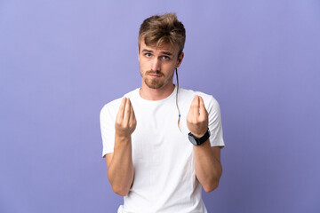 Young handsome blonde man isolated on purple background making money gesture but is ruined