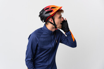 Young cyclist blonde man isolated on white background shouting with mouth wide open to the side