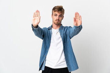 Young handsome man isolated on white background making stop gesture and disappointed