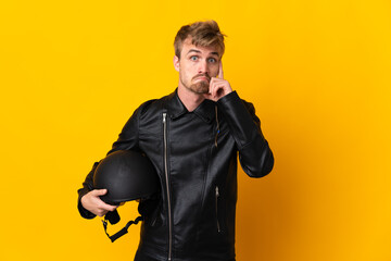 Man with a motorcycle helmet isolated on yellow background thinking an idea