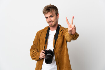 Young photographer blonde man isolated on white background smiling and showing victory sign