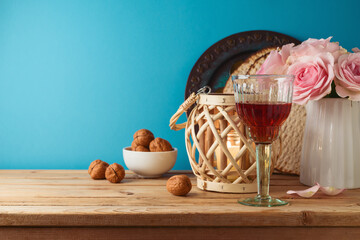 Jewish holiday Passover concept with wine glass, matzah and flowers on wooden table over blue...