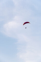 A paraglider or paramotor flying over a beautiful blue sky with white clouds over the beach.Real Photo