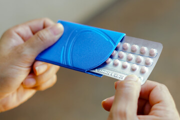 A woman holds her birth control pill. The medication is a pill that contains a combination of...