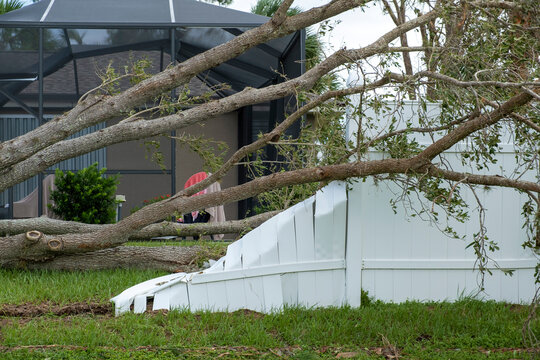 White plastic backyard fence damaged after hurricane winds in Florida. Aftermath of natural disaster
