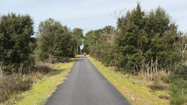 Piste cyclable bitum&eacute;e avec femme faisant du v&eacute;lo au lointain