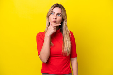 Young Uruguayan woman isolated on yellow background having doubts