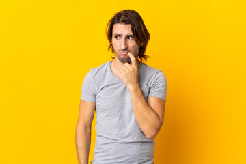 Young handsome man isolated on yellow background nervous and scared