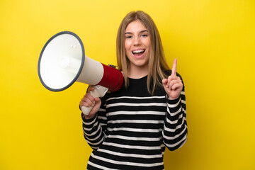Young caucasian woman isolated on yellow background holding a megaphone and pointing up a great idea