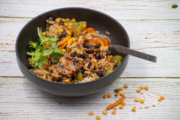 Vegan rice and mushroom pilaf, black bowl, wooden mat and table.. Chinese cuisine