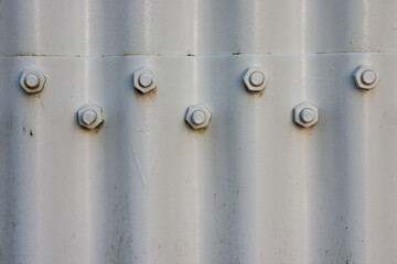Screws connecting white corrugated metal sheets together in a simple, monochrome image.