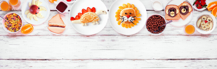 Fun child theme breakfast top border with an assortment of animal themed food. Overhead view on a white wood banner background. Pancakes, oatmeal, toast, fruit and cereal. - obrazy, fototapety, plakaty