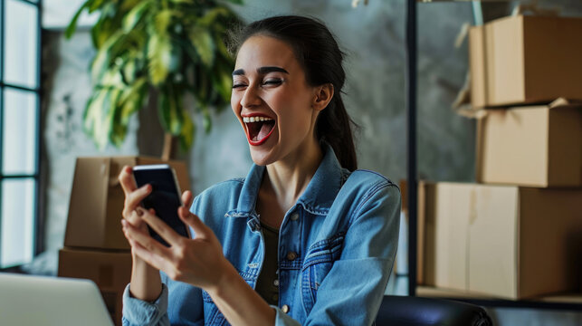 Joyful young woman looking at her phone, standing in a storeroom or warehouse environment filled with cardboard boxes
