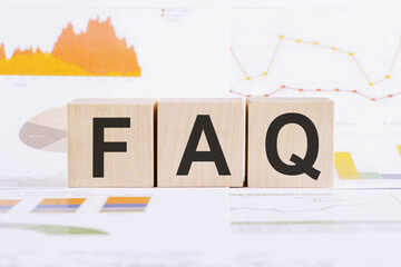 FAQ text on wood blocks on a document with tables