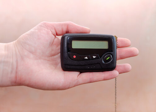 pager in close-up, an old retro communication device, in female hand on a beige background