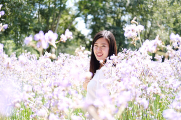 Beautiful Asian woman is smiling and relaxing in blooming purple Murdannia giganteum flowers field