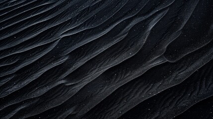 Obraz premium Detailed view of a dark-hued sand dune, showcasing its texture and shape in close proximity.