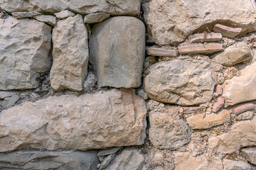 Background. An ancient wall made of archaically processed stone. The wall of the ancient building is made of stones.