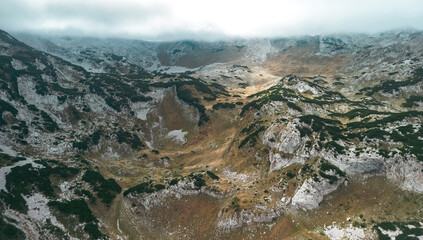 Drone shot of mountain peaks with rocky slopes, cliffs and scattered trees, Durmitor, Montenegro