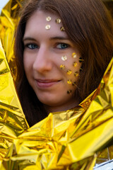 woman as a fantasy representation with tacks in her face and a golden rescue blanket