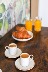 Cozy breakfast in the morning. Close up photo with orange juice, French croissants, coffee and milk or sugar on the site. Homemade breakfast.