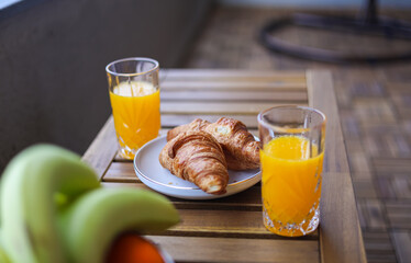 Coffee, croissants and orange juice on a dark stone table. Breakfast in the morning sun light.