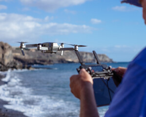 Senior man flying with drone at sunset using remote control. Aerial photographs. Sea and beach on background