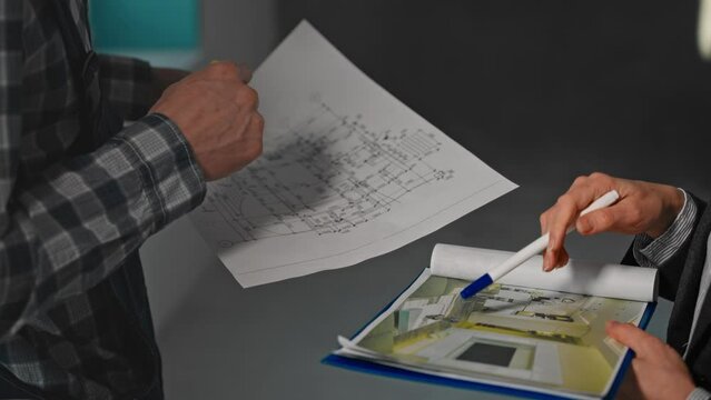 A man and a woman are gesturing at a blueprint of a house on paper