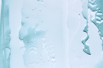 Abstract cosmetic background made of white cream on a blue background.