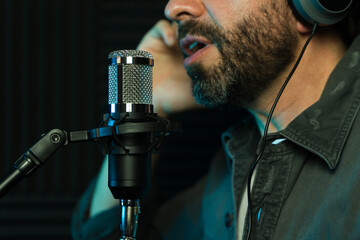 Closeup of a male vocalist recording  a song in a studio