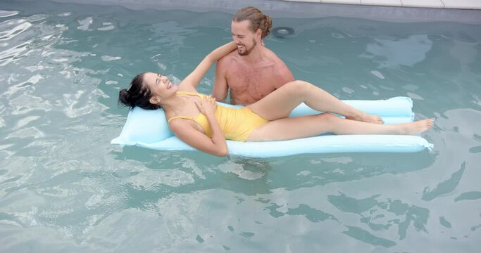 A young biracial couple enjoys a relaxing moment in a pool