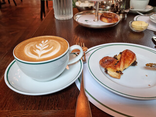 Breakfast table with cappuccino and pain au raisin bread