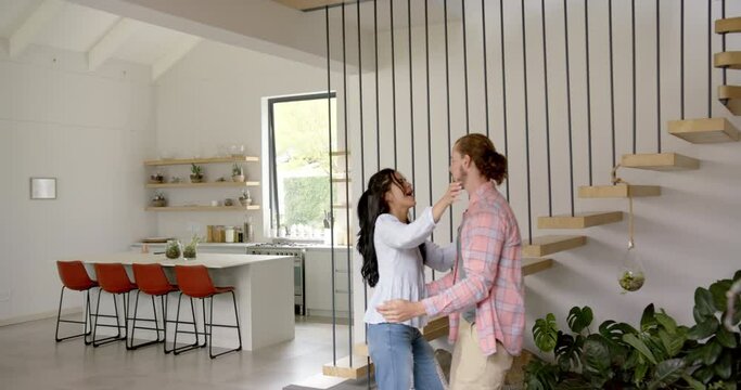 A young biracial couple is sharing a playful moment in a modern kitchen at home, copy space