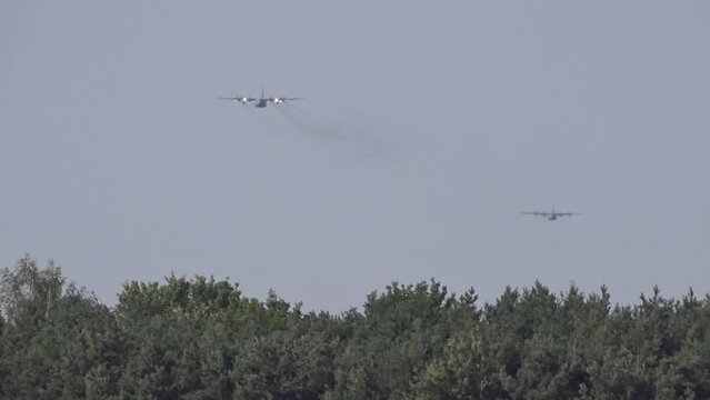 two old military transport aircraft airplanes flying above the trees to their target