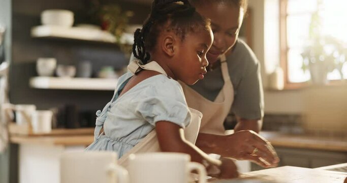 African, mom and child helping in kitchen and learning baking in home together with flour in morning. Black mother, cooking and teaching kid to clean table in preparation for bread or food in house