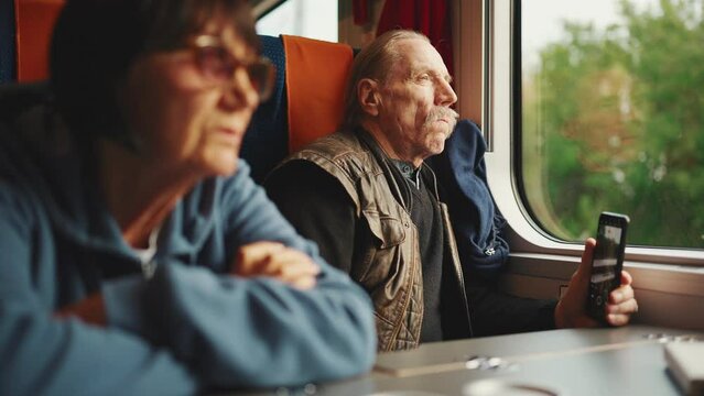 An elderly couple travels by train, Slow motion. An old husband and wife are traveling on a train.