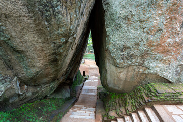 Tourists navigating the crevice between two large rocks at the exit of Sigiriya Rock after 5:30 PM. Dambulla, Sri Lanka.