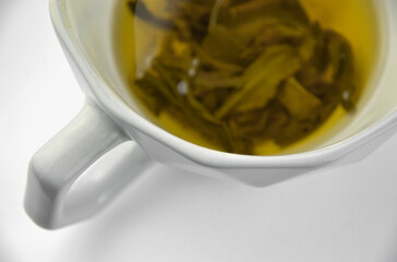 Ceramic geometry shaped gray cup of green tea on a white background, closeup, macro, top view