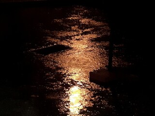 Una pozzanghera di pioggia, di notte, illuminata dalla luce di un lampione.