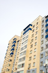 Fototapeta na wymiar Windows of multi-storey tall building against background of sky