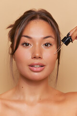 Closeup shot of pretty woman doing facial cosmetic procedure with moisturizing serum, skincare product concept, copy space