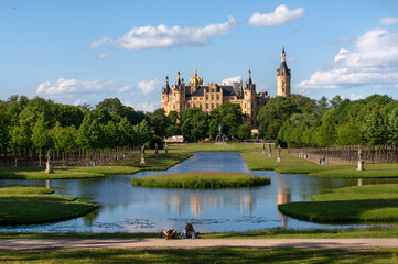 View through the palace gardens towards Schwerin Palace. Reflection in the water. Sunny day with...