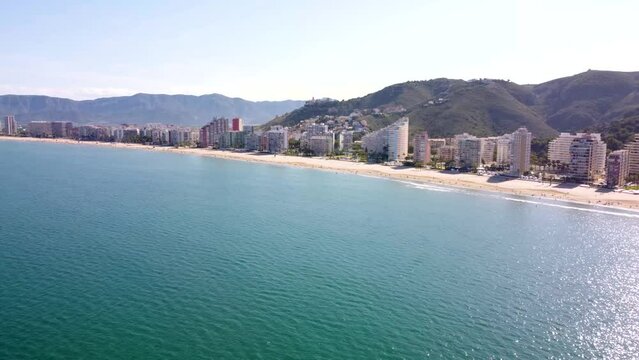 Drone view touring the first line of the beach of the town of Cullera in the province of Valencia (Spain) with apartment buildings along the beach