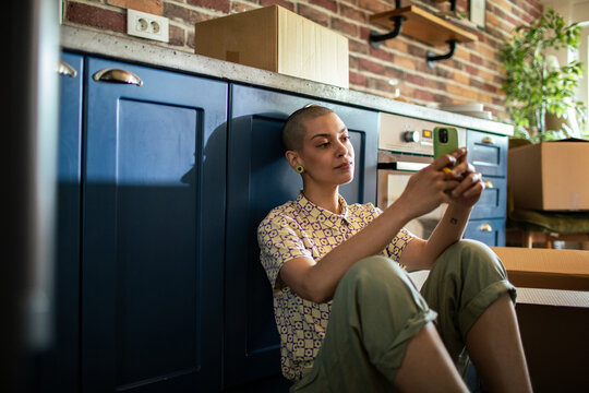 Woman using smartphone on floor with moving boxes around