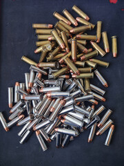 Two piles of .38 special caliber bullets with a fullmetal jacket tip, some are silver-colored and...
