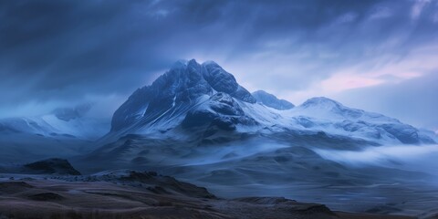 snow-capped mountain peaks under a moody blue twilight sky