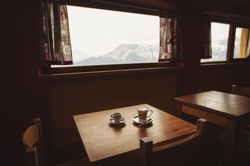 cups of espresso and cappucino against the mountains. hot coffee on wood table in wooden lodge at...